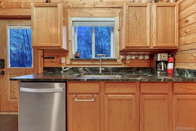 kitchen with dishwasher, dark stone counters, wooden walls, and a sink