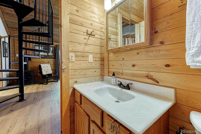 bathroom with wood walls, vanity, toilet, and wood finished floors