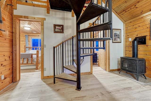 stairs featuring wood finished floors, wood ceiling, wood walls, and a wood stove