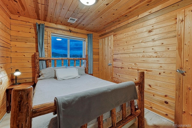 bedroom featuring visible vents, wooden walls, wood ceiling, and wood finished floors