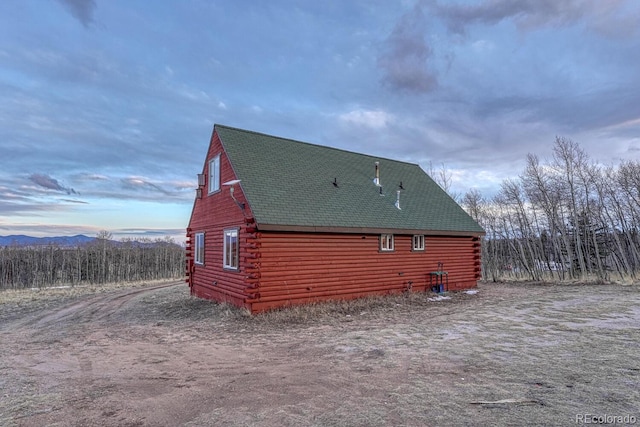 view of side of home featuring roof with shingles and log exterior