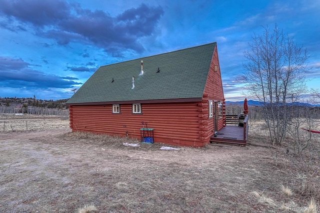 view of side of property with log siding, a deck, and a shingled roof