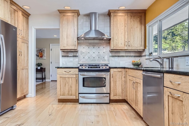 6227 Colorow Dr, Morrison, CO 80465 - kitchen with stainless steel appliances, tasteful backsplash, a sink, light wood-type flooring, and wall chimney range hood