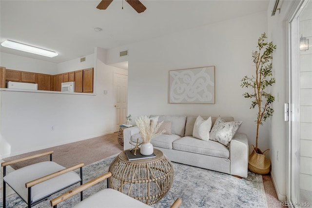 living room featuring ceiling fan, visible vents, and light colored carpet