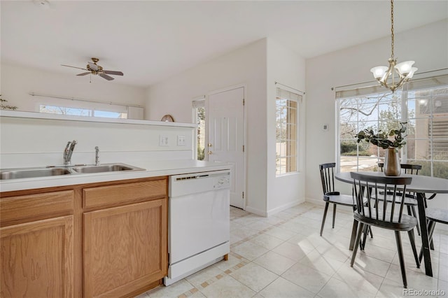 kitchen with white dishwasher, a sink, a healthy amount of sunlight, light countertops, and pendant lighting