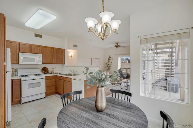 kitchen featuring light countertops, hanging light fixtures, visible vents, a sink, and white appliances