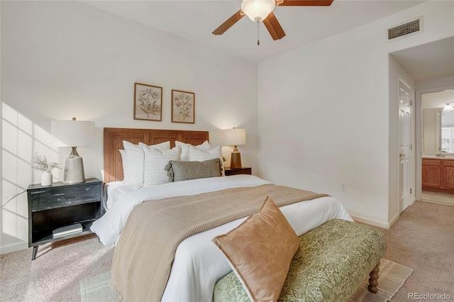 bedroom with light carpet, baseboards, visible vents, a ceiling fan, and ensuite bath