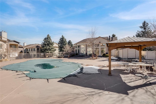 community pool with a patio area, fence, and a gazebo