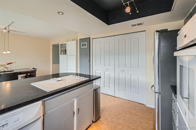 kitchen with white electric cooktop, light wood-type flooring, stainless steel refrigerator, pendant lighting, and white cabinets