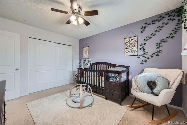 carpeted bedroom with ceiling fan, a textured ceiling, and a closet