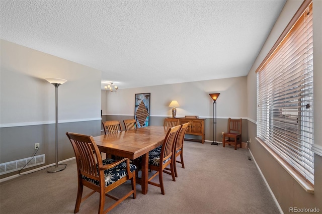 carpeted dining room featuring a textured ceiling and a notable chandelier