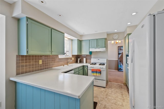 kitchen with kitchen peninsula, sink, backsplash, green cabinetry, and white appliances