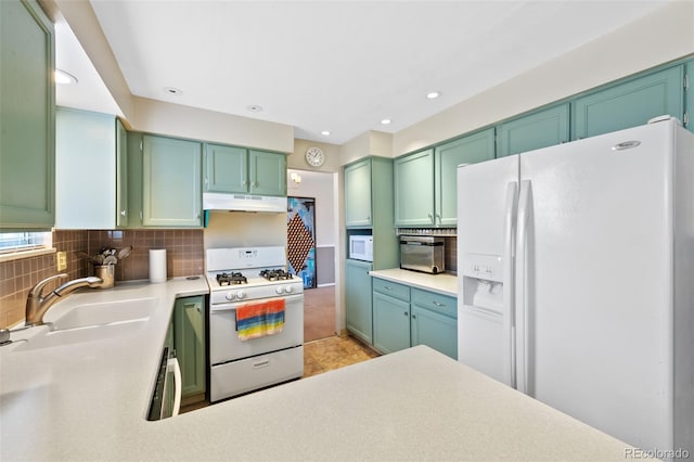 kitchen featuring sink, green cabinets, backsplash, and white appliances