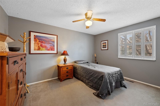 bedroom featuring ceiling fan, light carpet, and a textured ceiling