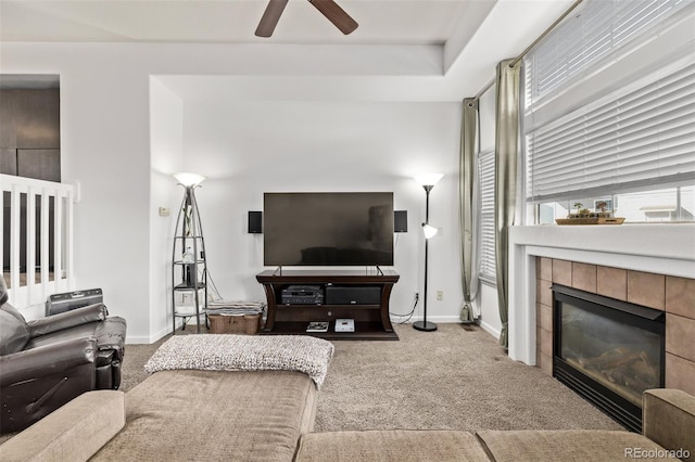 carpeted living area featuring a tiled fireplace, a ceiling fan, and baseboards