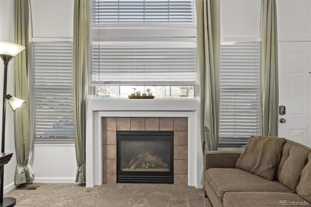 living room with baseboards, carpet, visible vents, and a tile fireplace