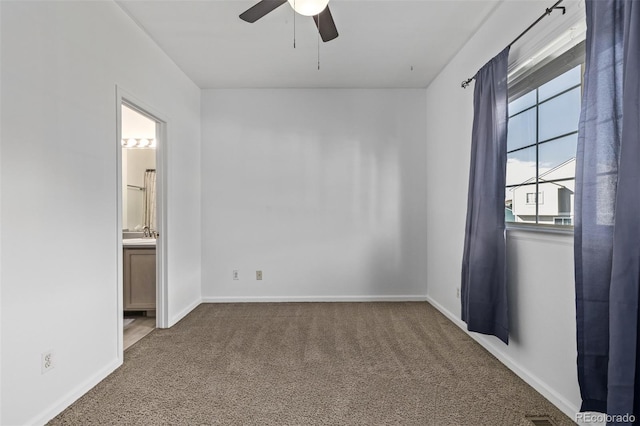 carpeted spare room featuring visible vents, baseboards, a ceiling fan, and a sink