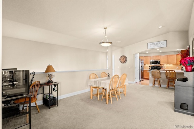 dining area featuring lofted ceiling and light colored carpet