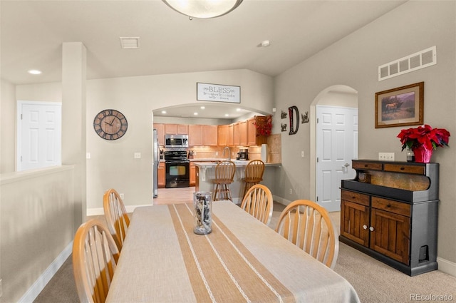 dining space featuring lofted ceiling and light carpet