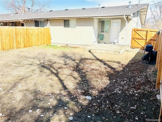 back of house featuring stucco siding, roof with shingles, and fence