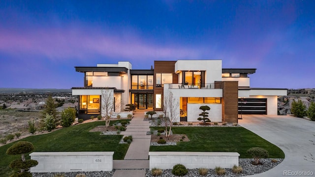 contemporary home with stucco siding, driveway, a balcony, and a front lawn