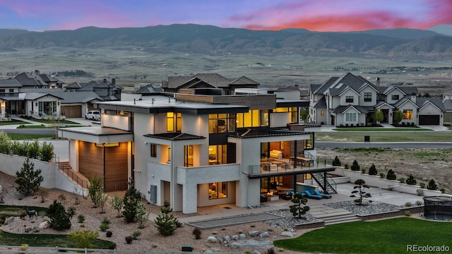 back of property at dusk with fence, a residential view, stairs, and a patio area