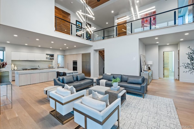 living room featuring recessed lighting, a high ceiling, an inviting chandelier, and light wood finished floors