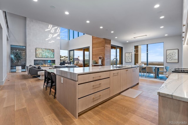 kitchen with light brown cabinets, open floor plan, a large island, modern cabinets, and light wood-type flooring