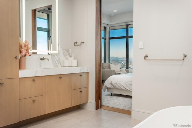 full bath featuring a healthy amount of sunlight, vanity, decorative backsplash, and a freestanding bath