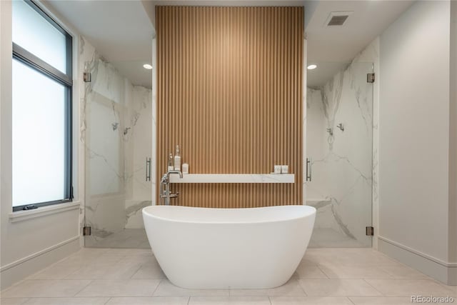 bathroom with a marble finish shower, plenty of natural light, a soaking tub, and visible vents