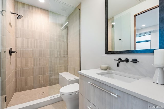 bathroom with vanity, recessed lighting, a tile shower, and toilet