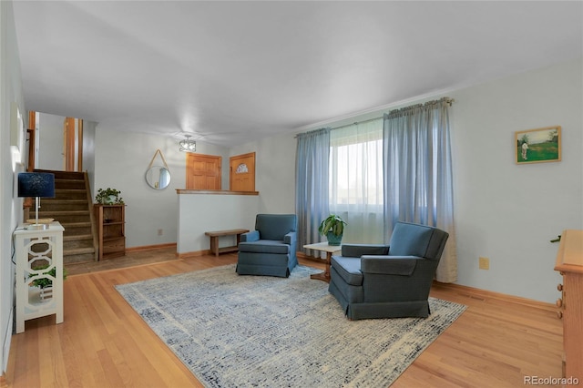 living area featuring stairs, light wood-style floors, and baseboards