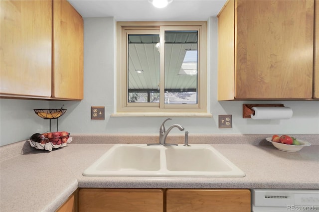 kitchen featuring dishwasher, light countertops, and a sink