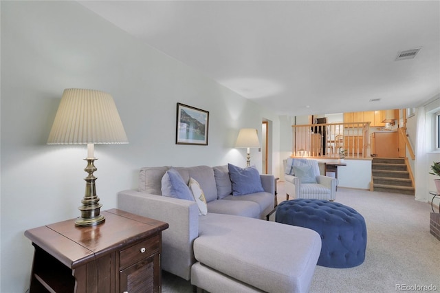 carpeted living area with stairs and visible vents