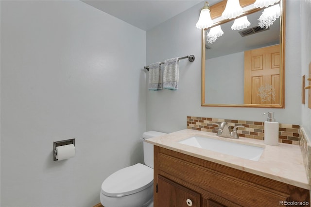half bathroom with backsplash, toilet, vanity, and visible vents