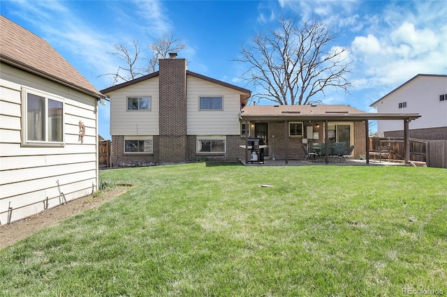 rear view of property with a lawn, fence, and brick siding