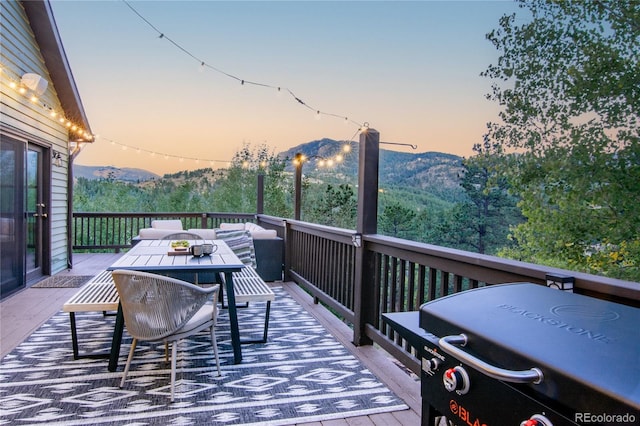 288 Spring Vly, Bailey, CO 80421 - deck at dusk with outdoor dining space, area for grilling, a mountain view, and an outdoor hangout area