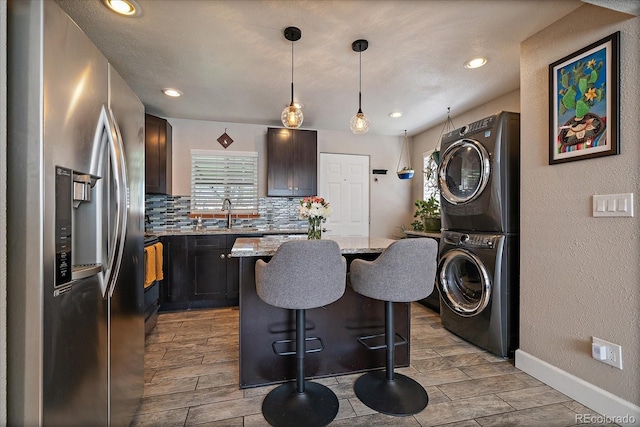 4530 S Pennsylvania St, Englewood, CO 80113 - kitchen with stacked washer / dryer, a kitchen bar, wood tiled floor, stainless steel refrigerator with ice dispenser, and light stone counters