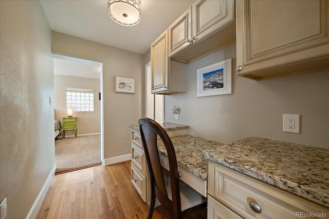 4530 S Pennsylvania St, Englewood, CO 80113 - kitchen with cream cabinets, light wood-type flooring, baseboards, built in study area, and light stone counters