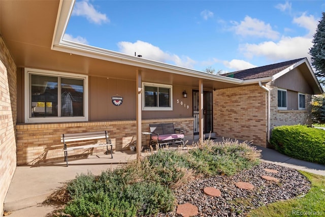 property entrance featuring a patio and brick siding