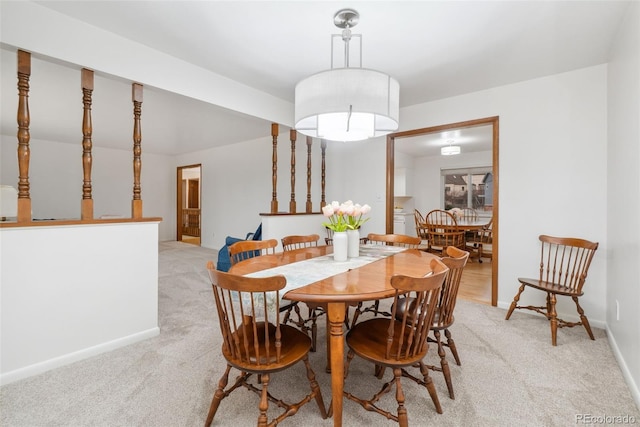 dining space featuring light colored carpet and baseboards