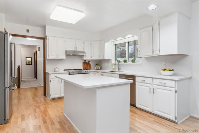 kitchen with freestanding refrigerator, light countertops, white cabinets, under cabinet range hood, and range with electric stovetop