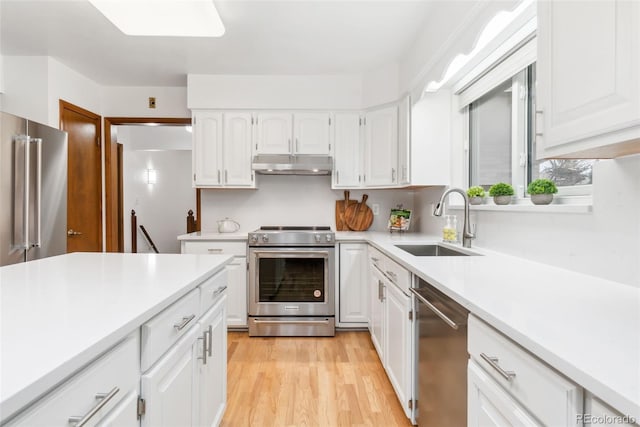 kitchen featuring under cabinet range hood, appliances with stainless steel finishes, light countertops, and a sink