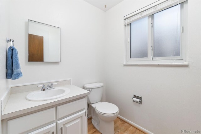 bathroom with baseboards, toilet, wood finished floors, and vanity