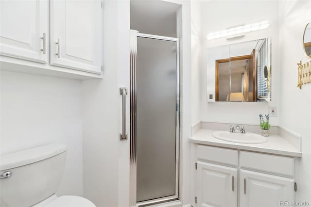 bathroom with a stall shower, toilet, and vanity