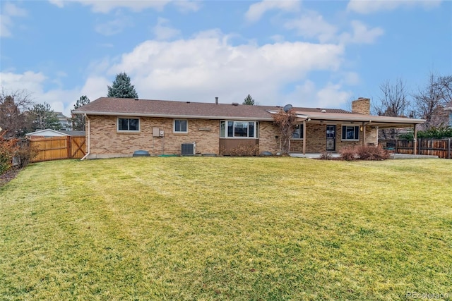 back of property with a yard, a fenced backyard, a chimney, and central AC