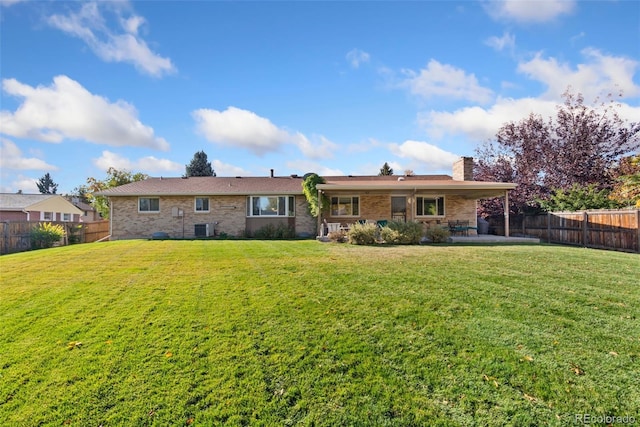 rear view of property with central air condition unit, a lawn, a chimney, a fenced backyard, and a patio