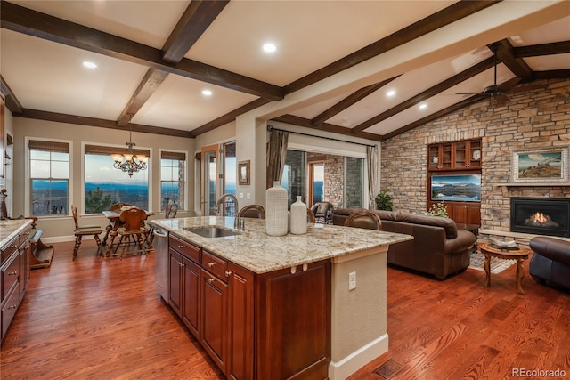 kitchen with dark wood-style flooring, dishwasher, light stone countertops, and a sink