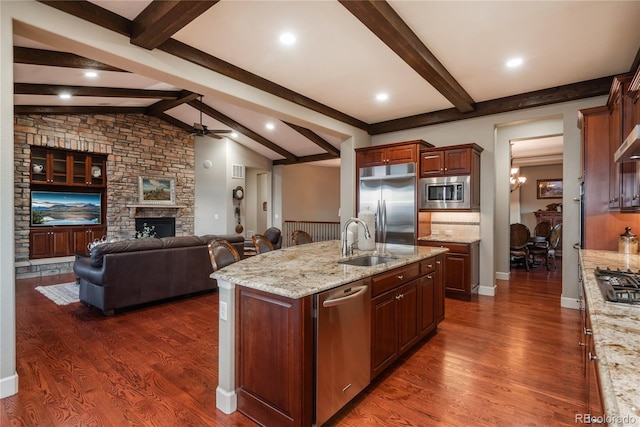 kitchen featuring dark wood-style floors, built in appliances, open floor plan, and a sink