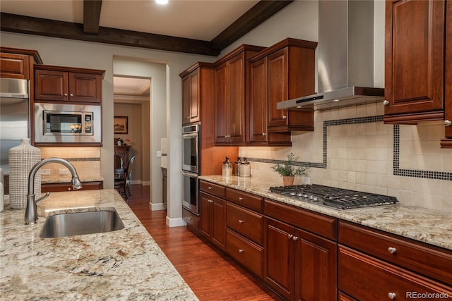 kitchen featuring beamed ceiling, dark wood-style flooring, a sink, stainless steel appliances, and wall chimney range hood